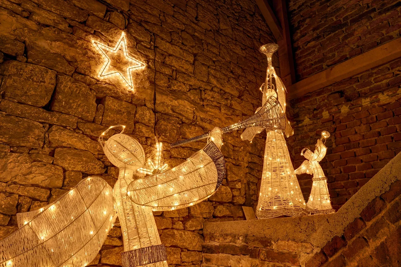 Ange LED blanc chaud à la trompette de 122 cm à côté d'un renne lumineux et d'un sapin avec des étoiles, scène hivernale devant un mur